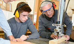 Meister zeigt Lehrling Arbeit mit Schneidemaschine