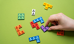 Hand schiebt Dominosteine mit Personenicons ineinander, so dass sie zusammen passen. 
